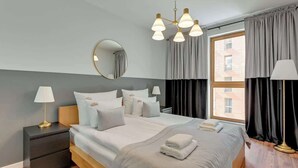 A modern hotel room with a large bed, bedside tables, a mirror, and a window with curtains. - Aura 196B | Riverside | City Center (Gdańsk)