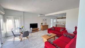 Ein modernes Wohnzimmer mit einem roten Sofa, einem Glastisch und einem Fernseher.