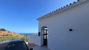 Ein weißes Gebäude mit einem Ziegeldach, einer Tür und Blick aufs Meer.