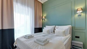 Une chambre d’hôtel avec un lit, deux lampes de chevet, une table de chevet et une fenêtre avec des rideaux.