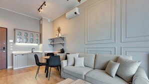 Un salon moderne comprenant un canapé, une table à manger avec des chaises, un coin cuisine avec des placards et une étagère intégrée.