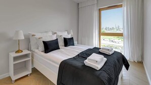 A hotel room with a bed, a nightstand, a lamp, and a window with curtains.