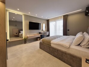 A modern hotel room with a large bed, a desk, a flat-screen TV, and a large mirror.