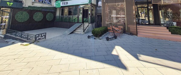 A paved area with a staircase leading to a building entrance, a sign for 'TEB,' and a 'D'BACELINA' store with a mannequin display.