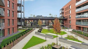 Un edificio moderno con varios pisos, zonas de estar al aire libre y un puente peatonal.