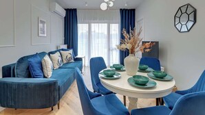 Una sala de estar moderna con un sofá azul, una mesa de comedor con platos verdes y un jarrón decorativo.