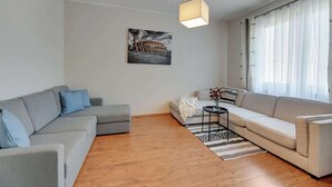 A modern living room with a grey sofa, a white sofa, a black coffee table, and a wooden floor. - Gdynia | 800 metres to the beach | City Centre (Gdynia)
