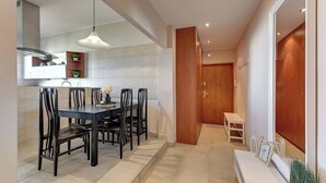 A modern kitchen with a dining area, a wooden door, and a bench with decorative items. - Gdynia | 800 metres to the beach | City Centre (Gdynia)