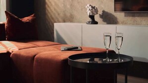 A modern room with a sofa, a round table with two glasses, a vase, and a painting on the wall. - Scala 9 with Terrace | City Center | Parking (Gdańsk)