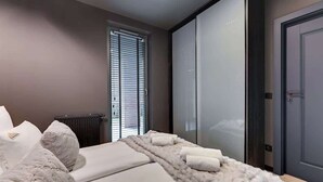 A bedroom with a bed, a fur throw, and a window with blinds. - Scala 9 with Terrace | City Center | Parking (Gdańsk)