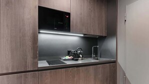 A modern kitchen with wooden cabinetry, a built-in microwave, a kettle, and a sink. - Scala 9 with Terrace | City Center | Parking (Gdańsk)