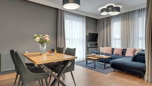 Un salon moderne comprenant une table à manger, des chaises, un canapé et un téléviseur.