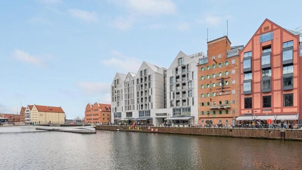 Un hôtel situé au bord de l’eau, doté d’une architecture moderne, d’une promenade le long de la rivière et présentant une variété de styles architecturaux.