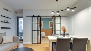 En moderne stue med sofa, spisebord med stole, en skydedør og udsigt ud