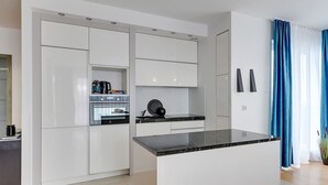 Una cocina moderna con armarios blancos, una isla con encimera negra y un horno empotrado.