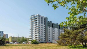 Un hotel a più piani dal design moderno, con balconi su ogni piano, un’area di parcheggio antistante e un prato nelle vicinanze.
