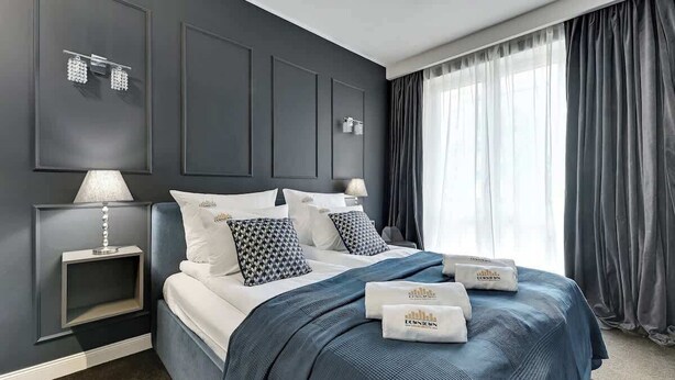 Camera d'albergo moderna con un letto grande, pareti scure e vista sull'esterno.