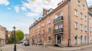 Una strada acciottolata con un edificio di due piani, caratterizzato da balconi e un ingresso al piano terra.