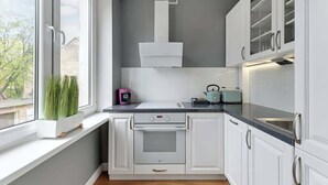 Una cucina moderna con mobili bianchi, forno integrato, una finestra con vista e una parete grigia.