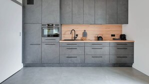 A modern kitchen with grey cabinetry, a wooden countertop, and a built-in oven. - Horizontal Sea & City view | Gdynia | 3 bedrooms (Gdynia)