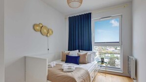 A bedroom with a bed, a window, a radiator, and a small table with a lamp. - Horizontal Sea & City view | Gdynia | 3 bedrooms (Gdynia)