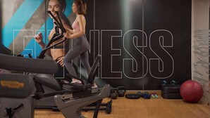 Et fitnesscenter med træningsudstyr, vægte og en stor væg med ordet 'EXERCISE'.