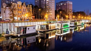 A waterfront area with moored boats, a row of buildings, and a reflection on the water. - Houseboat Aurora | Old Town | Romantic | Sauna (Gdańsk)