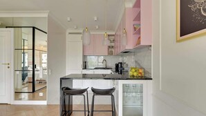 A modern kitchen with a central island, bar stools, and pendant lighting. - Rezydencja Wintera 1 | River View (Gdańsk)