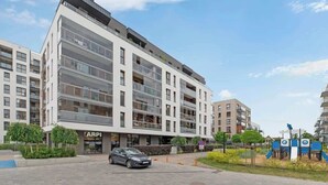 A multi-story building with a modern design, featuring balconies and large windows. - Zajezdnia Wrzeszcz 9 | Balkony | Parking (Gdańsk)