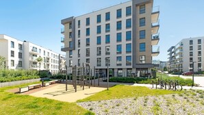 A modern multi-story residential building with balconies, a playground, and a bike parking area. - Przystań Letnica 20 | Comfortable Stay & Parking (Gdańsk)