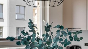 A modern kitchen with a clear vase of eucalyptus branches on the counter. - Przystań Letnica 20 | Comfortable Stay & Parking (Gdańsk)