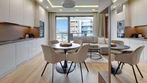 Um apartamento moderno com área de refeições, cozinha e varanda com vista para a cidade.