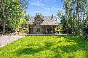 A wooden house with a tiled roof, a covered porch, and a well-maintained lawn.