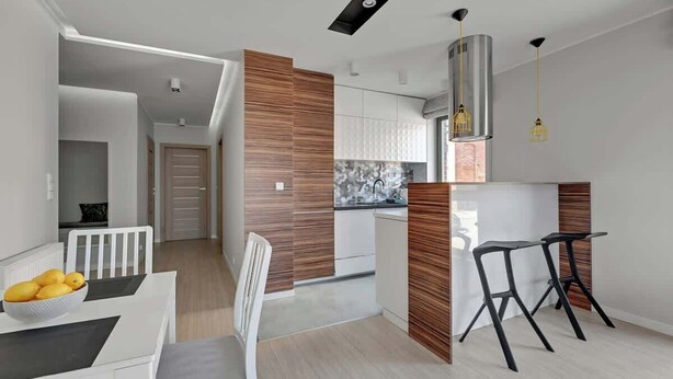 A modern kitchen with a central island, white cabinetry, and a built-in stove. - Browar Gdański | Best Location (Gdańsk)