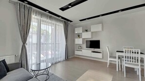 A modern living room with a sofa, TV, dining table, and chairs. - Browar Gdański | Best Location (Gdańsk)
