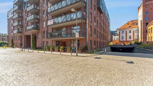 A multi-story building with balconies, a cobblestone ground, and a sign indicating a business. - Browar Gdański | Best Location (Gdańsk)