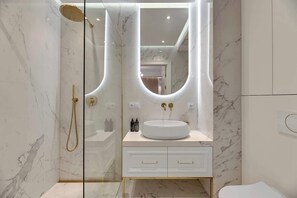 Une salle de bain moderne avec une douche à parois de verre, un lavabo rond et un meuble-lavabo avec des tiroirs.
