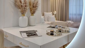 Um quarto moderno com uma cama branca, uma mesa de cabeceira com abajur e vista da cidade através de grandes janelas.