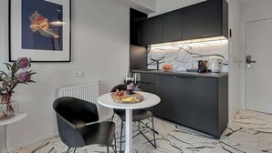 Una cocina moderna con armarios oscuros, encimera blanca y una zona de comedor con una mesa redonda y dos sillas.