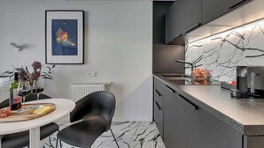 Una cocina moderna con encimera de mármol, sillas negras y una obra de arte enmarcada en la pared.