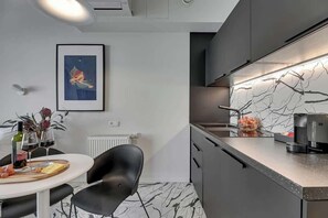 A modern kitchen with a marble countertop, black chairs, and a framed artwork on the wall. - DeoPlaza207B | Best view in Gdansk | SPA | Balcony (Gdańsk)
