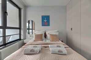 Ein Hotelzimmer mit Bett, Fenster, Heizkörper, einem Wandspiegel und einem gerahmten Bild.