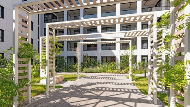 Un immeuble à plusieurs étages doté d’un espace extérieur abrité, agrémenté d’une structure en forme de pergola.