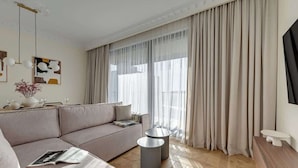 Een moderne woonkamer met een hoekbank, een ronde salontafel en een televisie op een houten kast.