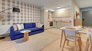 Una sala de estar moderna con un sofá azul, una mesa de centro y un comedor con una mesa y sillas blancas.