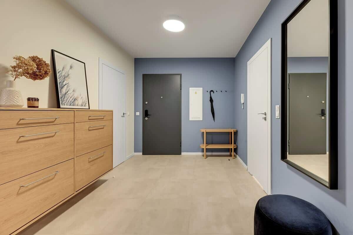 Ein Flur mit einem Holzschrank, einer Bank, einem Spiegel und einer Tür.