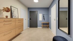 Un pasillo con un aparador de madera, un banco, un espejo y una puerta.