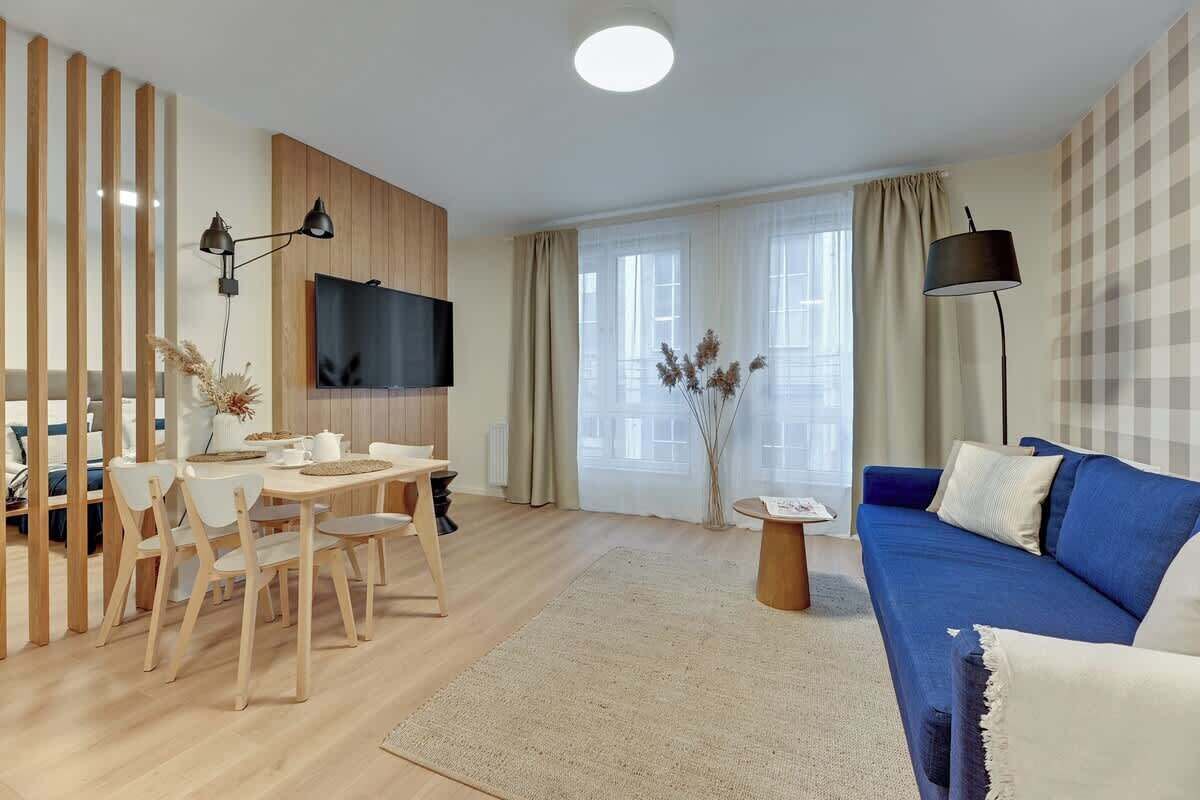 Ein modernes Wohnzimmer mit Fernseher, Sofa, Esstisch, Stühlen und einer Lampe.