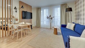 Una sala de estar moderna con televisión, sofá, mesa de comedor, sillas y una lámpara.