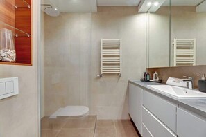 Un baño moderno con ducha, inodoro y tocador con espejo.